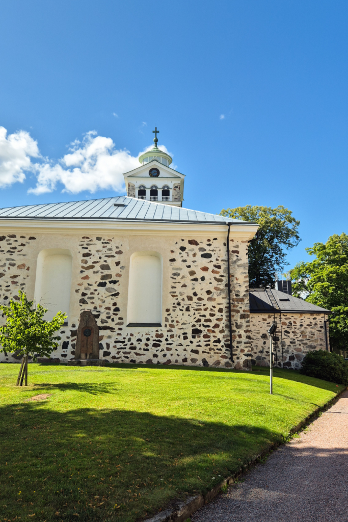 Tammisaari church surrounded by greenery on a sunny summer day.