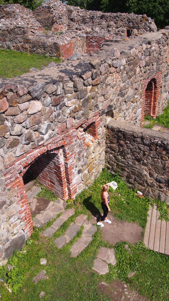 Me exploring the historic Kuusiston linnanrauniot (Kuusisto Castle Ruins) in Finland, surrounded by ancient stone walls on a sunny summer day