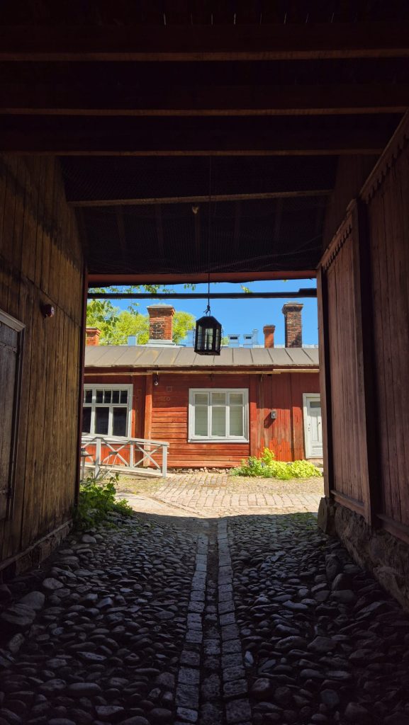 Entry to Café Qwensel on cobblestone street with wooden houses in Turku, Finland.
