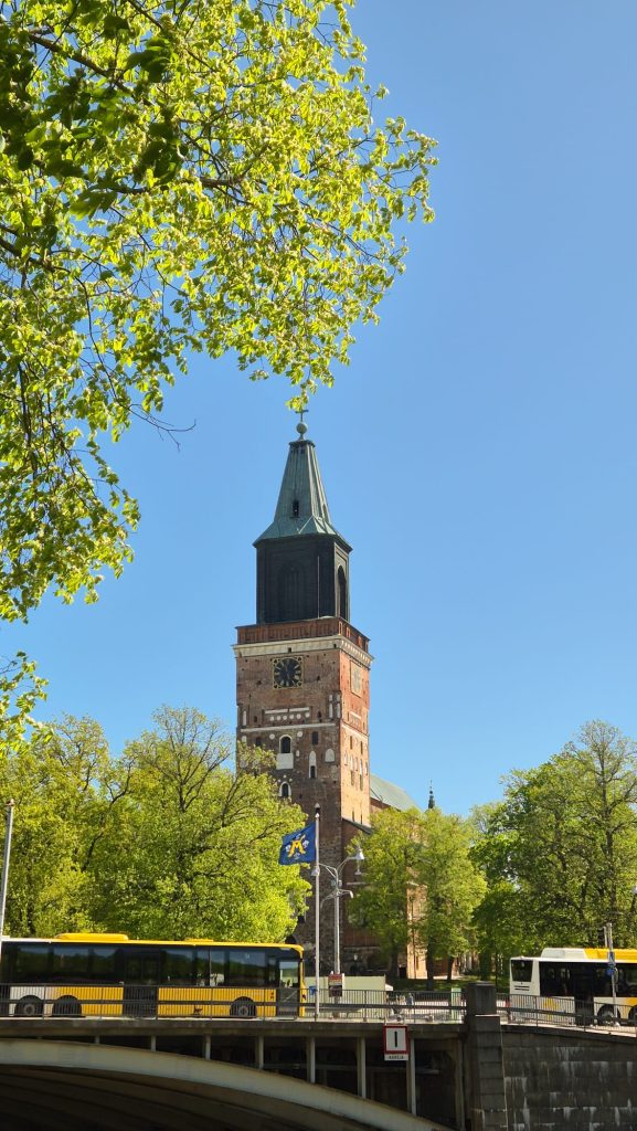 View of Turku Cathedral with yellow city buses passing by on a sunny summer day in Turku, Finland.