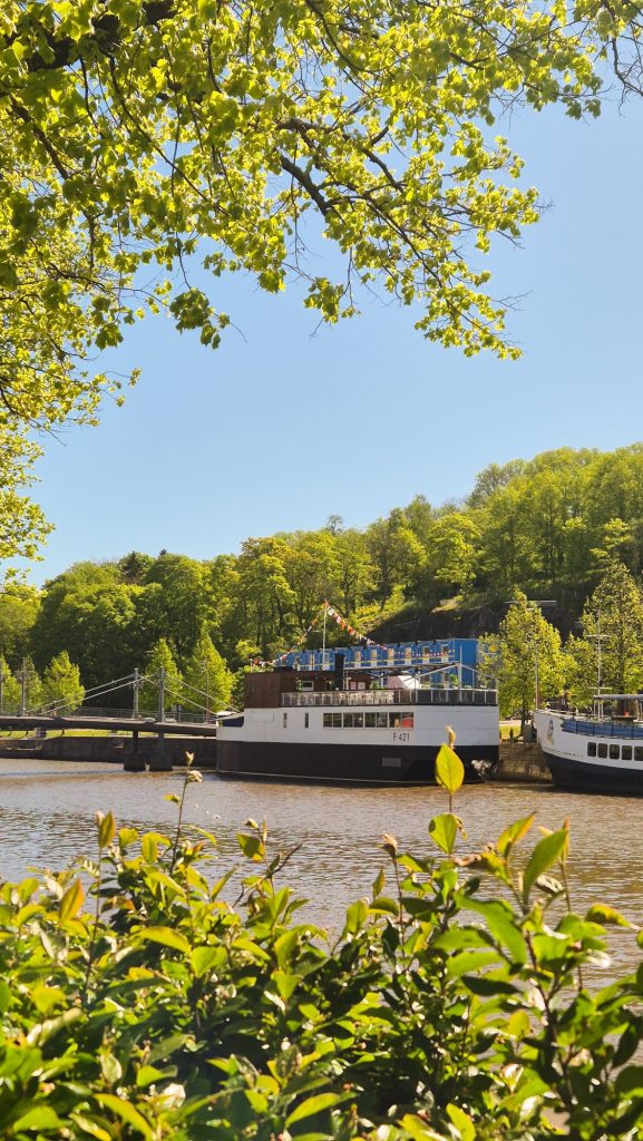 Aura River in Turku with riverboat cruising and lush greenery, summer day in Finland.