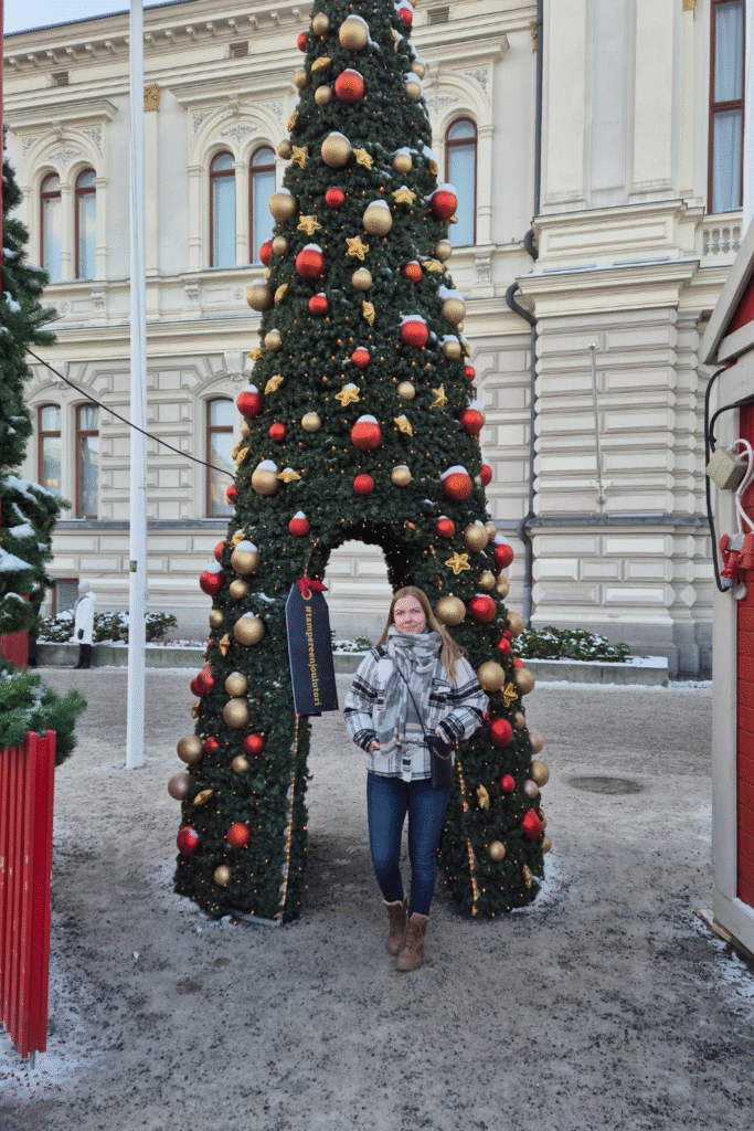 Visiting Tampere Christmas Market with festive tree decorations in the background.