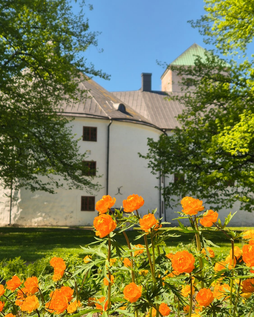 Turku Castle surrounded by colourful summer flowers on a sunny day in Finland.