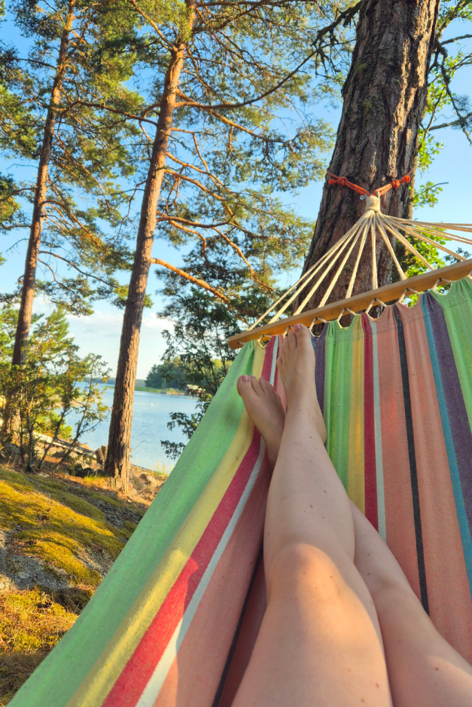 Person relaxing in a hammock while enjoying the peaceful sea view on a summer day in Finland.
