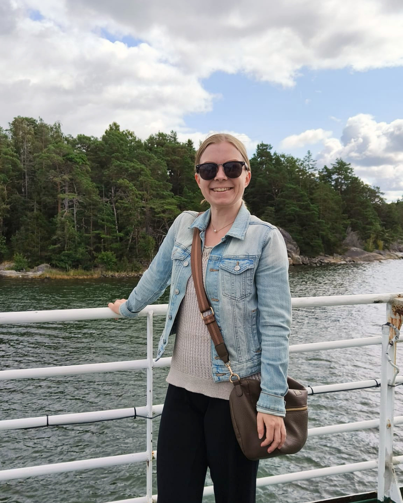 Woman standing on the deck of a boat to Seili Island with the Finnish Archipelago in the background.