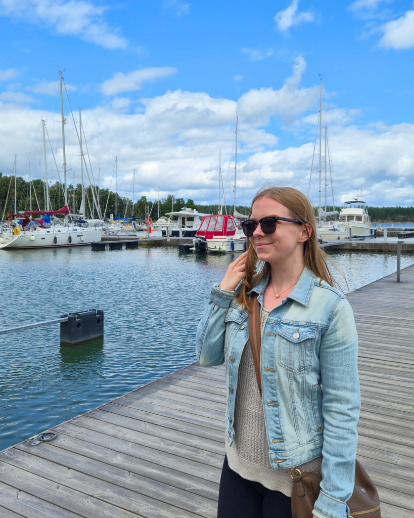 Woman standing at Nauvo harbour with boats and the sea in the background.