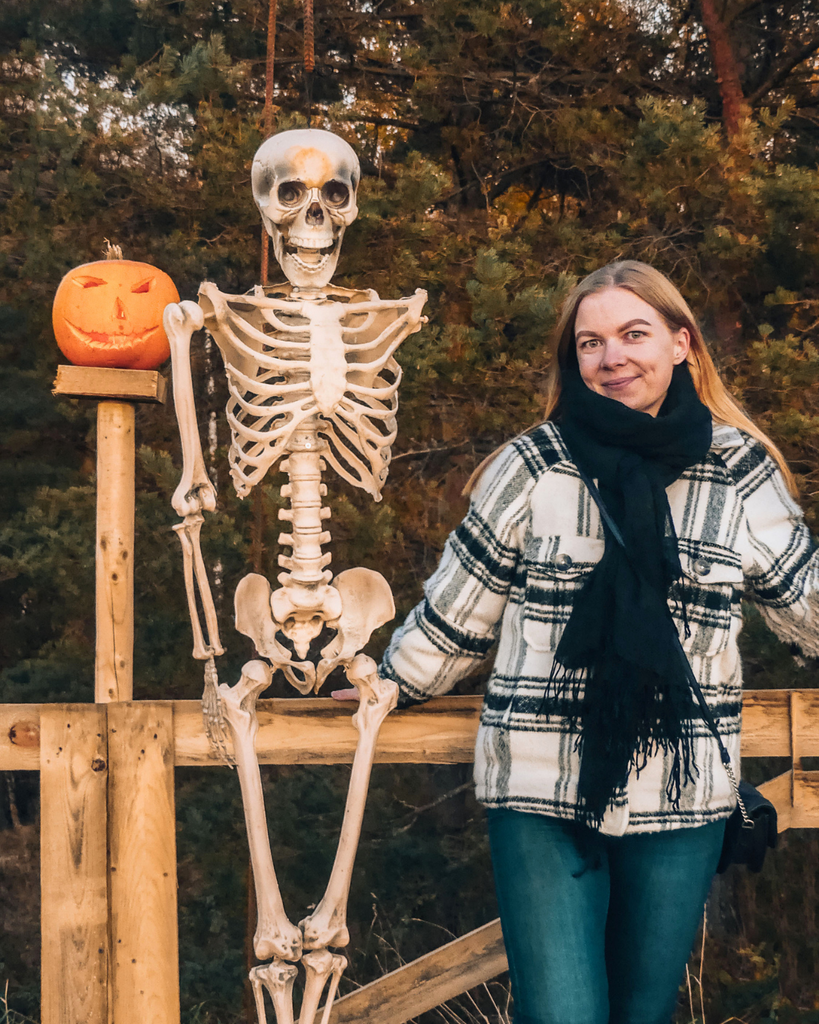 A woman posing with a skeleton Halloween decoration at Salo Pumpkin Park in Finland.