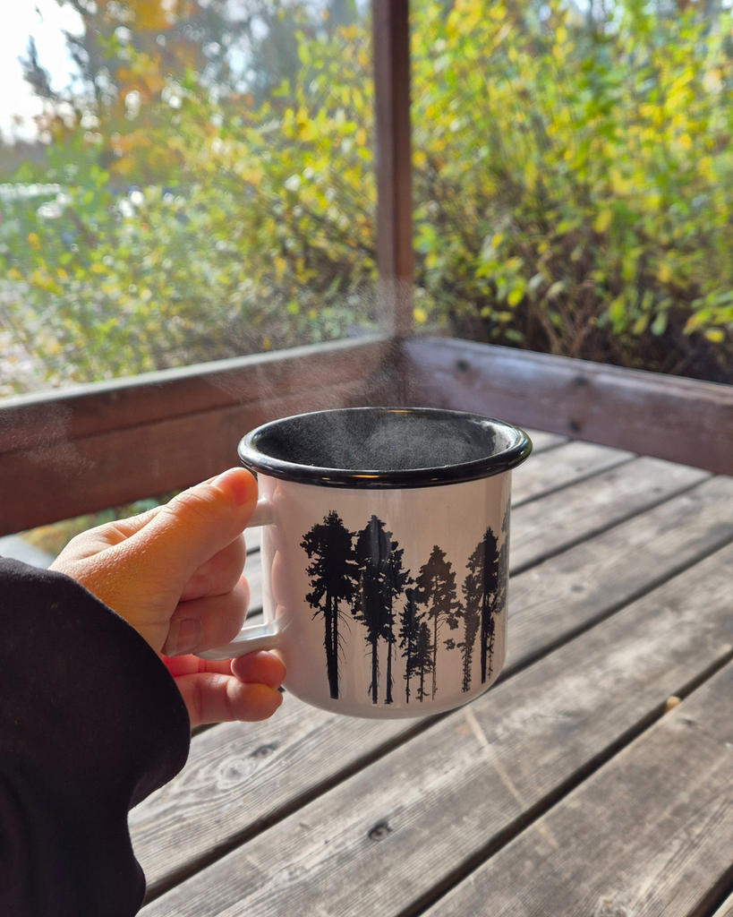 Woman on an autumn hike in Finland holding a warm cup with steam rising from it, surrounded by fall foliage.