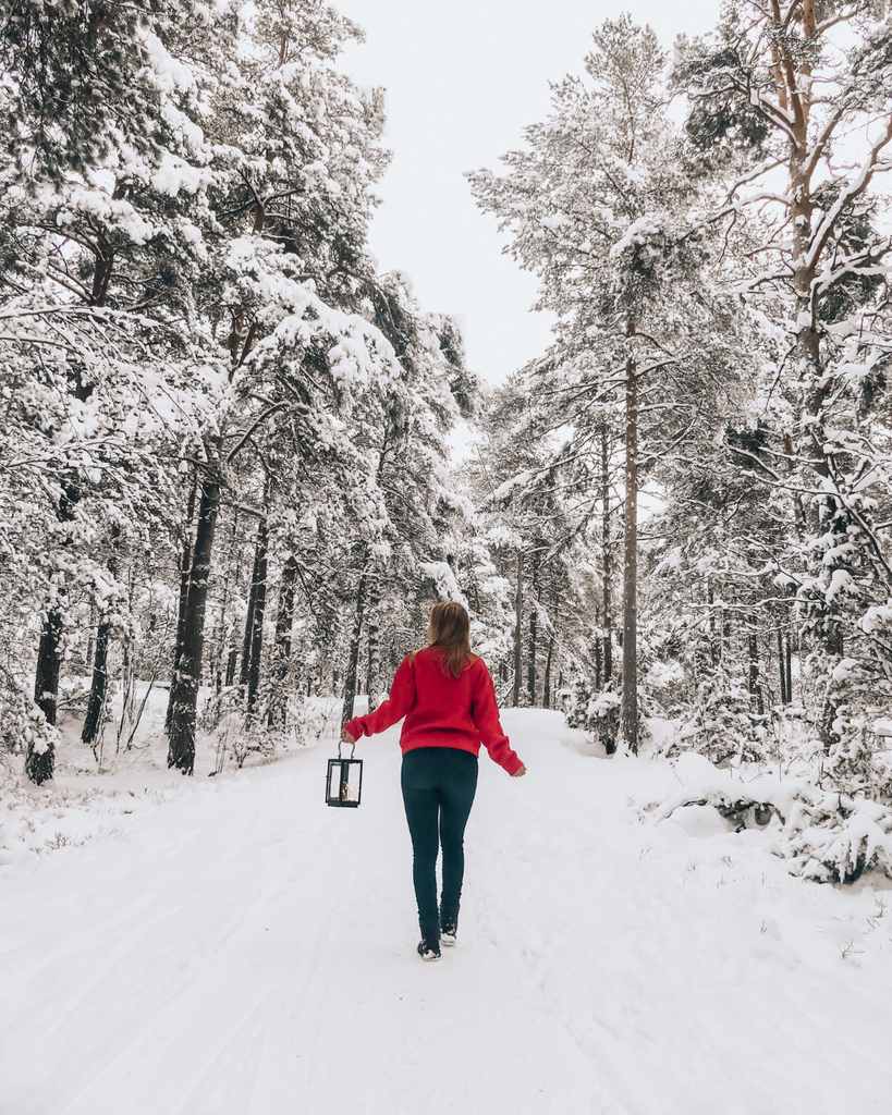 A person walking through a snow-covered Finnish forest in winter.