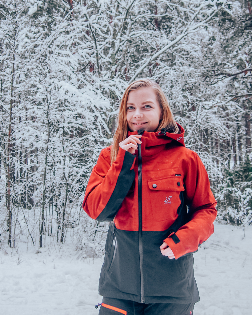 A person wearing a winter jacket in a snow-covered Finnish forest.