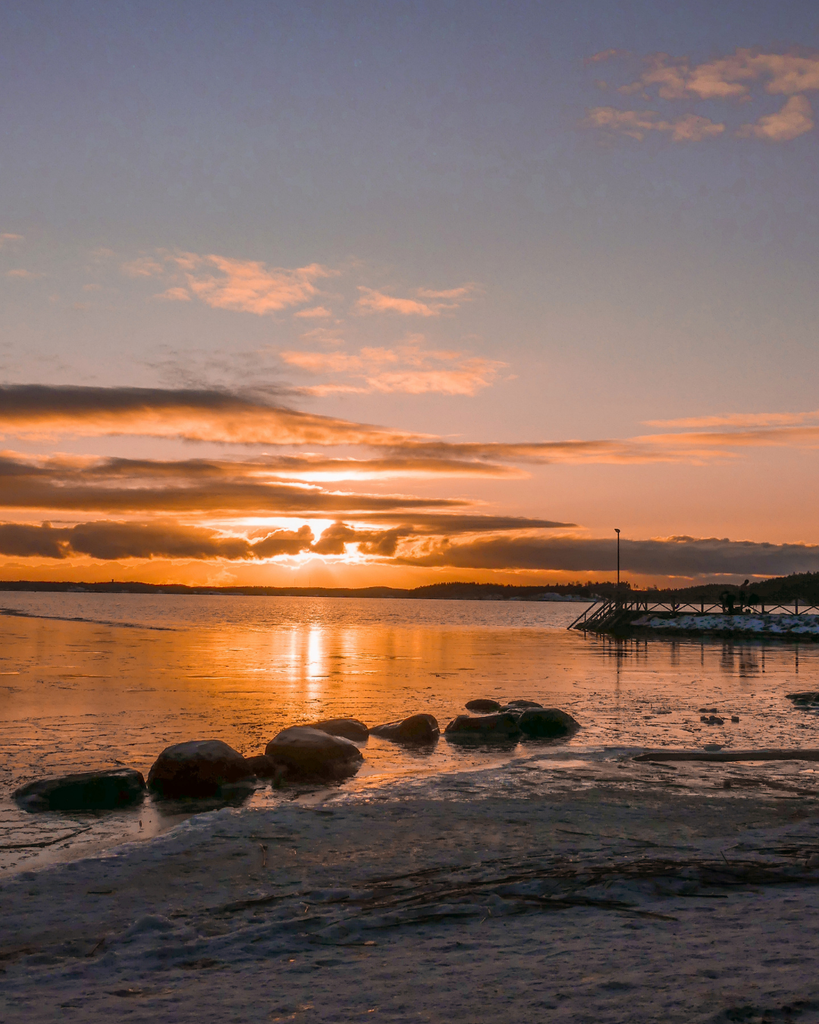 Winter sunset over the sea in Ruissalo, Turku, with the sky glowing above the horizon.