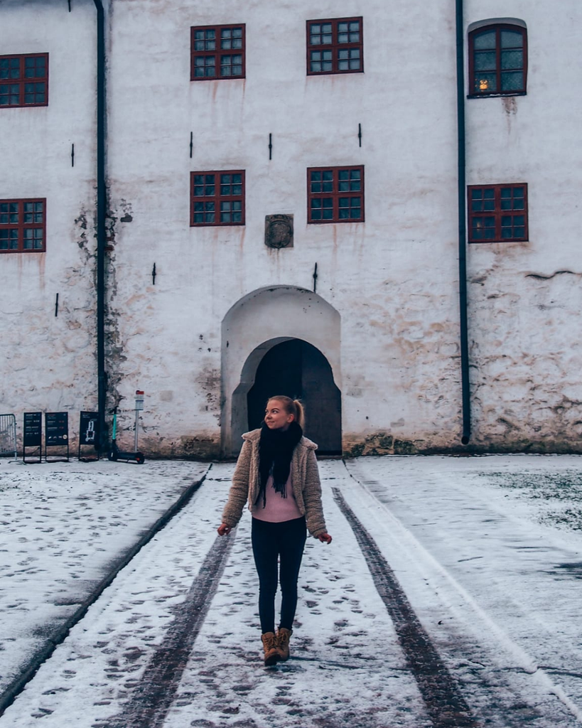 Visitor walking in front of Turku Castle on a snowy winter day in Turku, Finland.