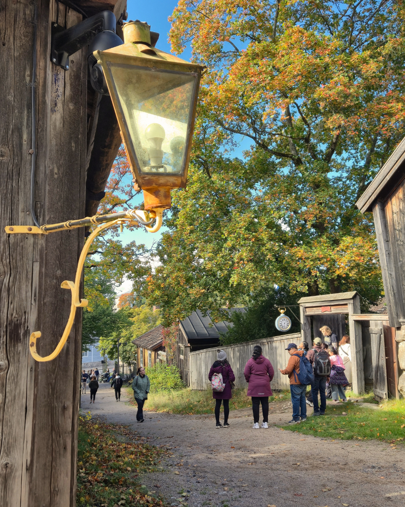 Visitors walking along a historic street on an autumn day at Luostarinmäki Handicrafts Museum in Turku, Finland.