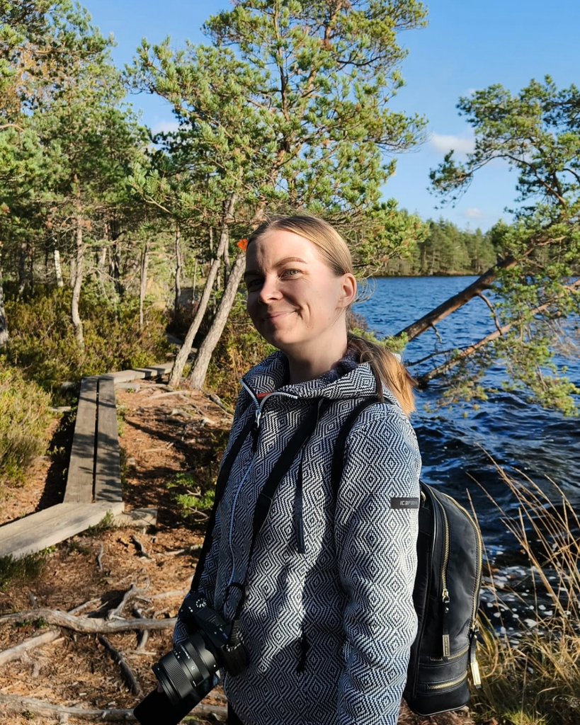 Woman smiling at the camera while hiking the Savojärvi Trail in Kurjenrahka National Park on a sunny autumn day.