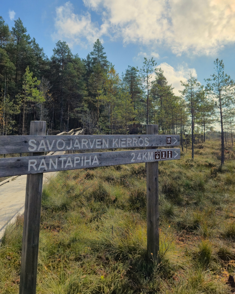 Wooden Savojärvi Trail sign marking the hiking route in Kurjenrahka National Park, Southwest Finland.